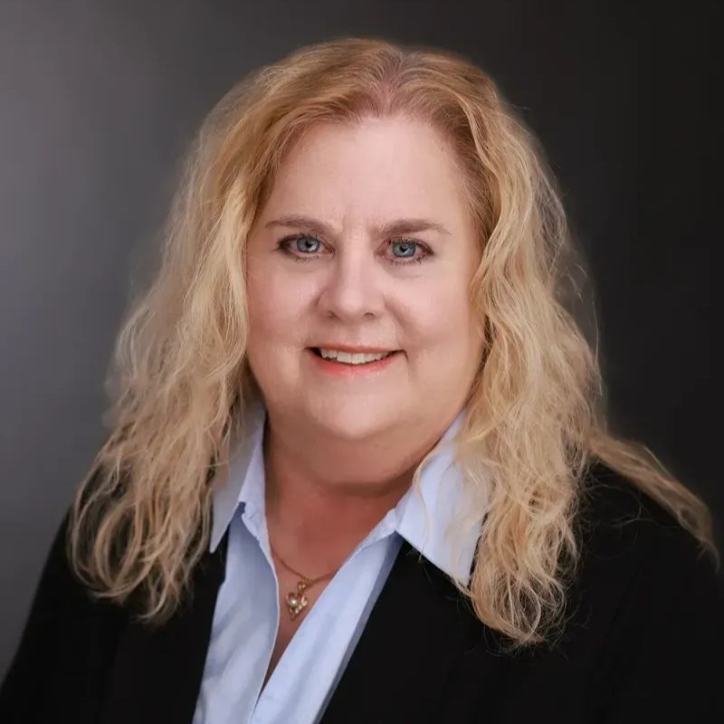 Dr. Dana Day, audiologist, smiling in a light blue blouse and black jacket